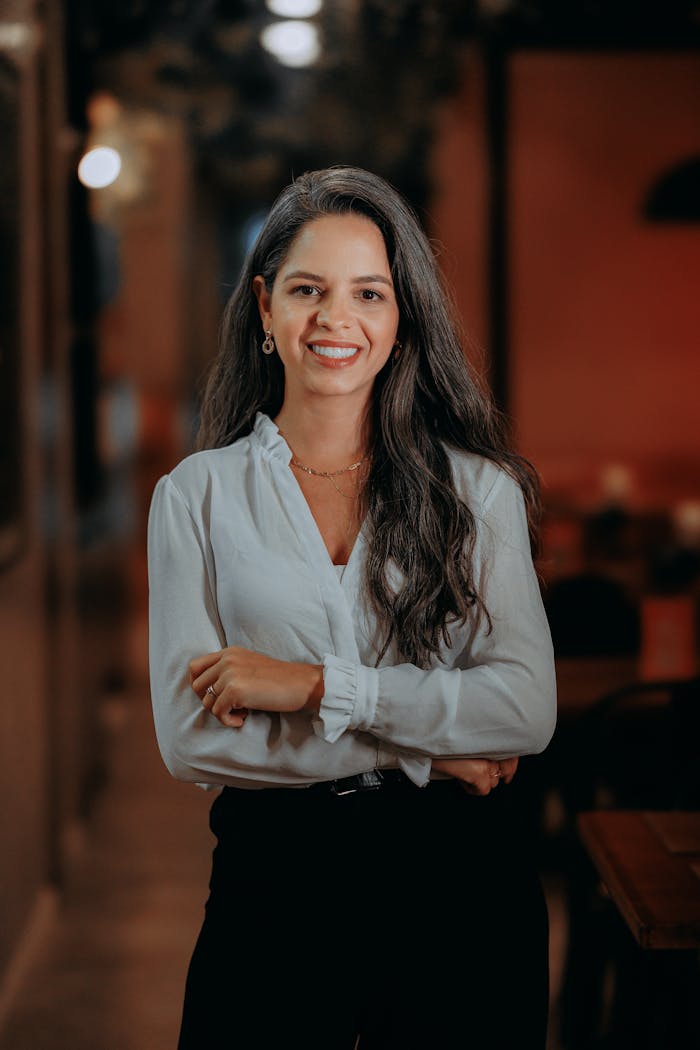 gallery-3 Confident businesswoman with long hair smiling in an indoor office setting.