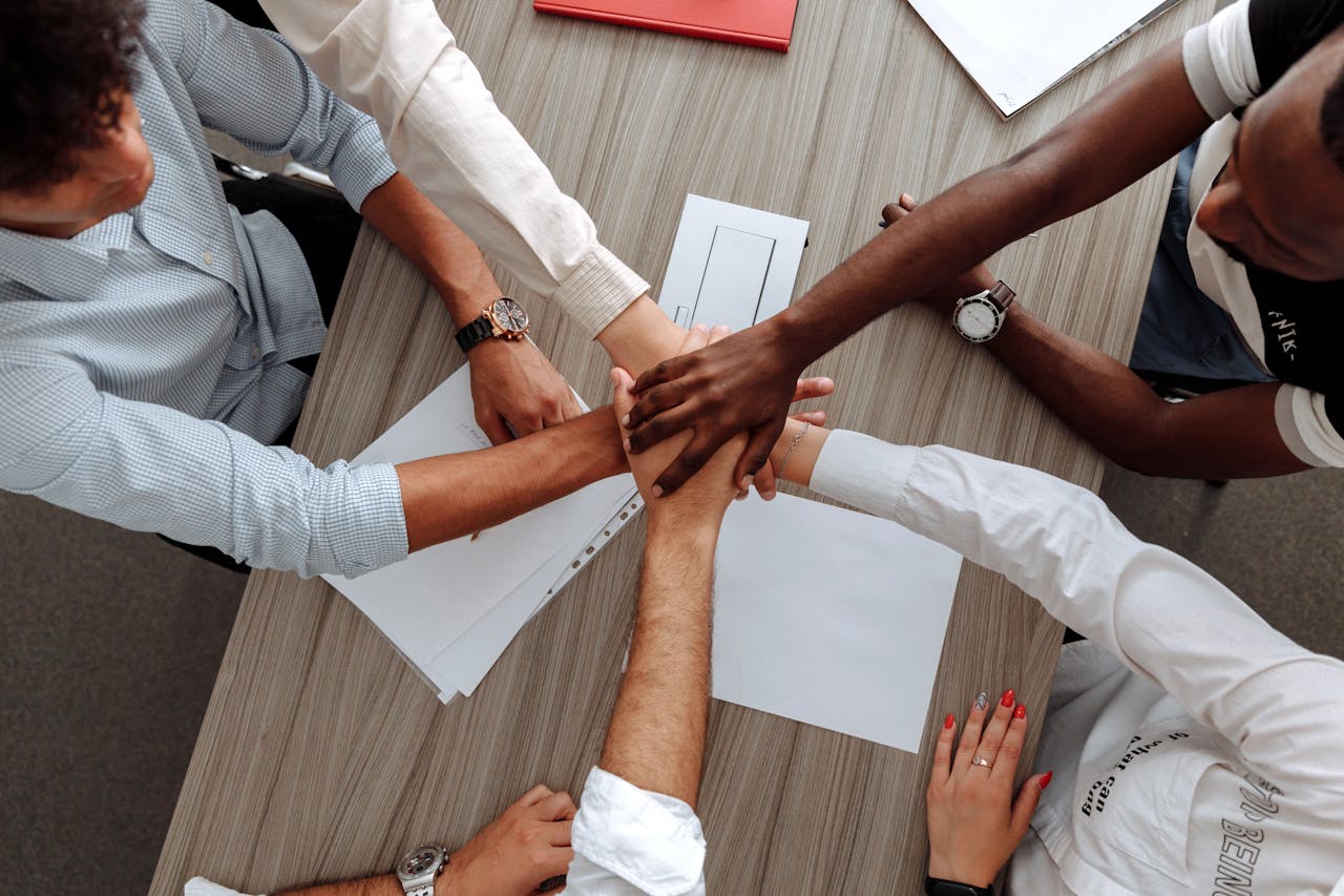 services-img A diverse group of adults join hands in an office, symbolizing teamwork and cooperation.