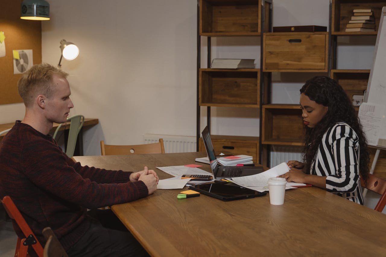 about-01 Two professionals engaged in a business meeting at a modern office, discussing strategies.